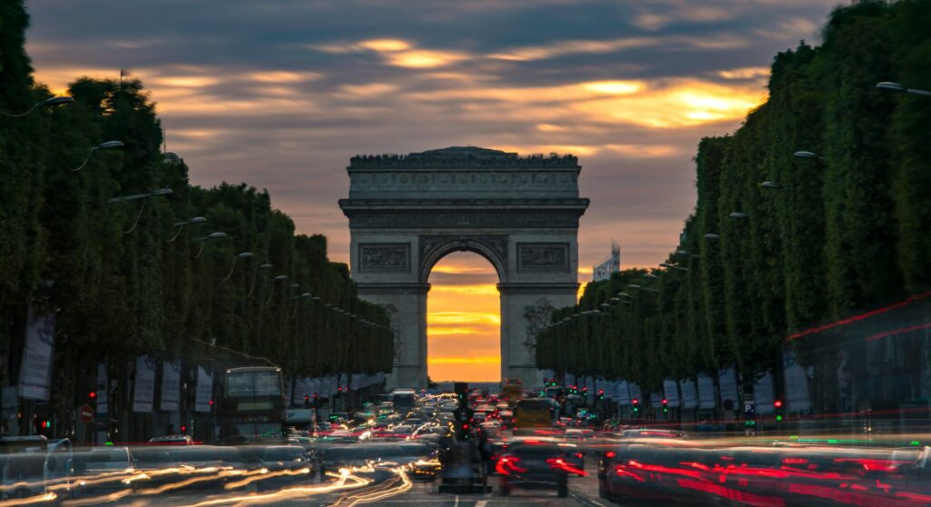 Arc de triomphe au couché de soleil. Dense circulation de voiture